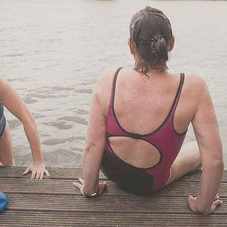 A woman sitting on the edge of a pier in her bathing suit