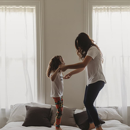 A woman jumping on a bed with her daughter