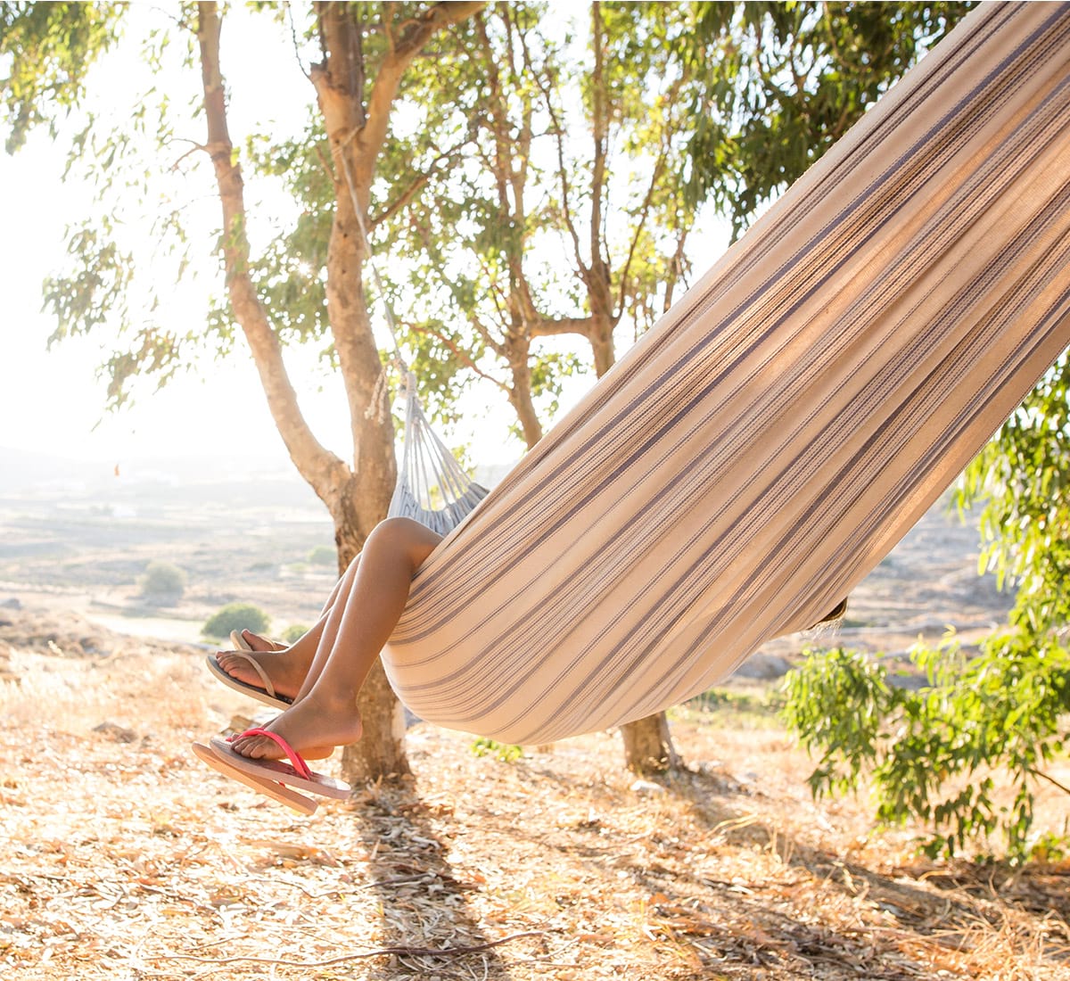A couple relaxing in a hammock, only their feet are exposed in a remote section of nature
