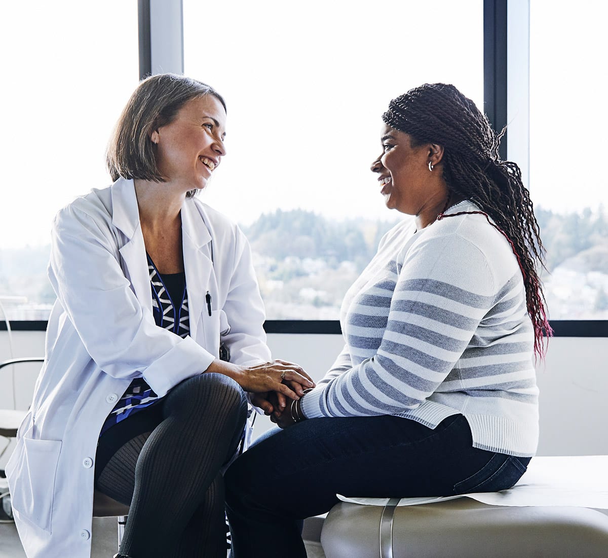 A smiling female physician consulting a smiling female patient
