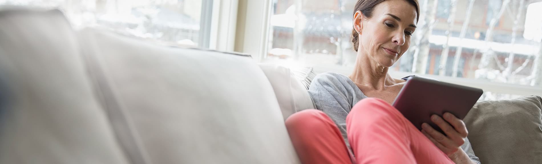 A middle-aged woman relaxing at home, viewing information on her tablet