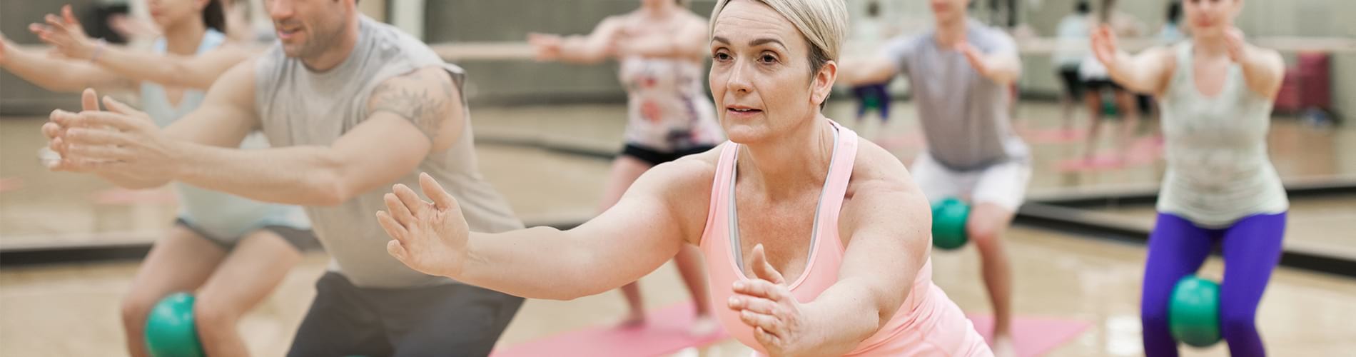An older woman performing yoga in a classroom of other people