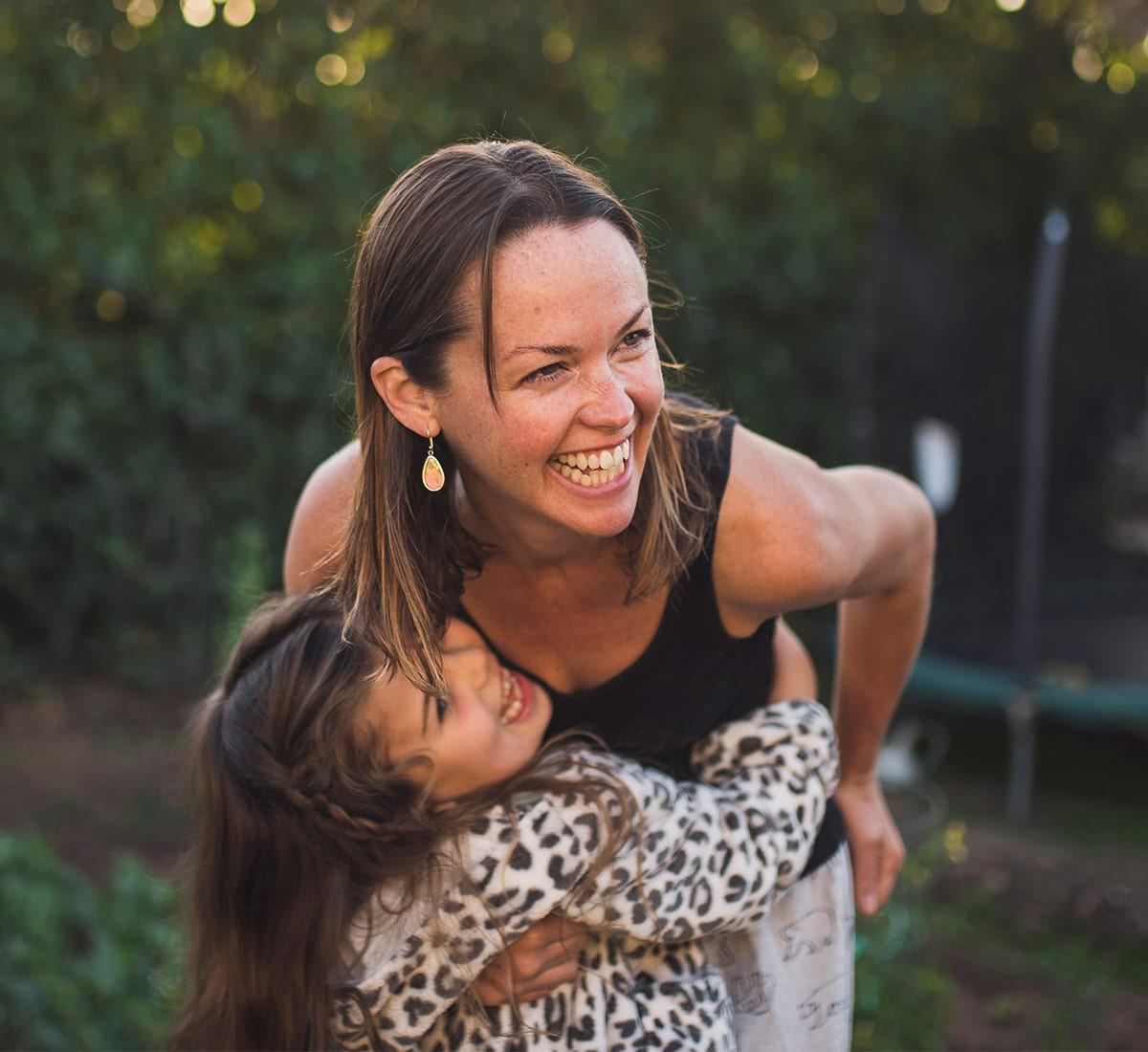 A mother and daughter playing in their backyard hugging and smiling