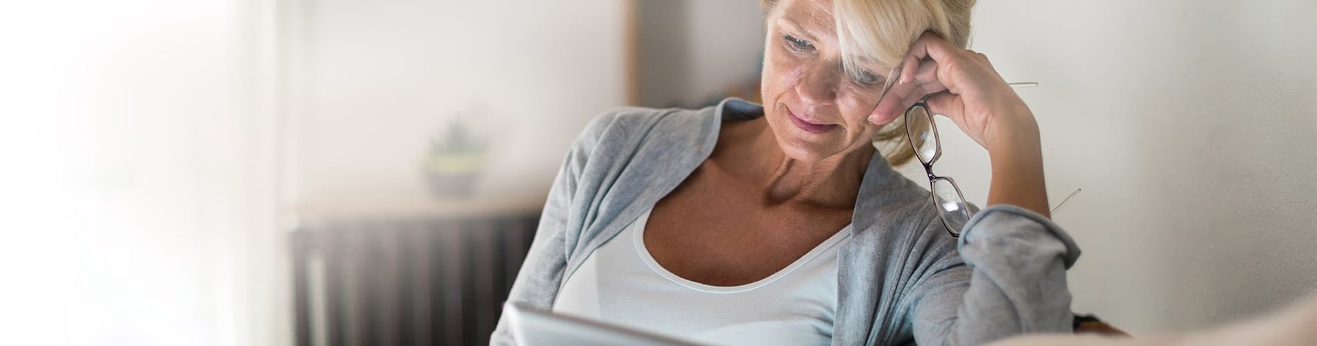 An older woman staring inquisitively at a laptop computer screen in her home