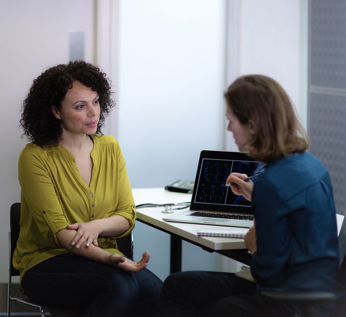A smiling female physician consulting a smiling female patient