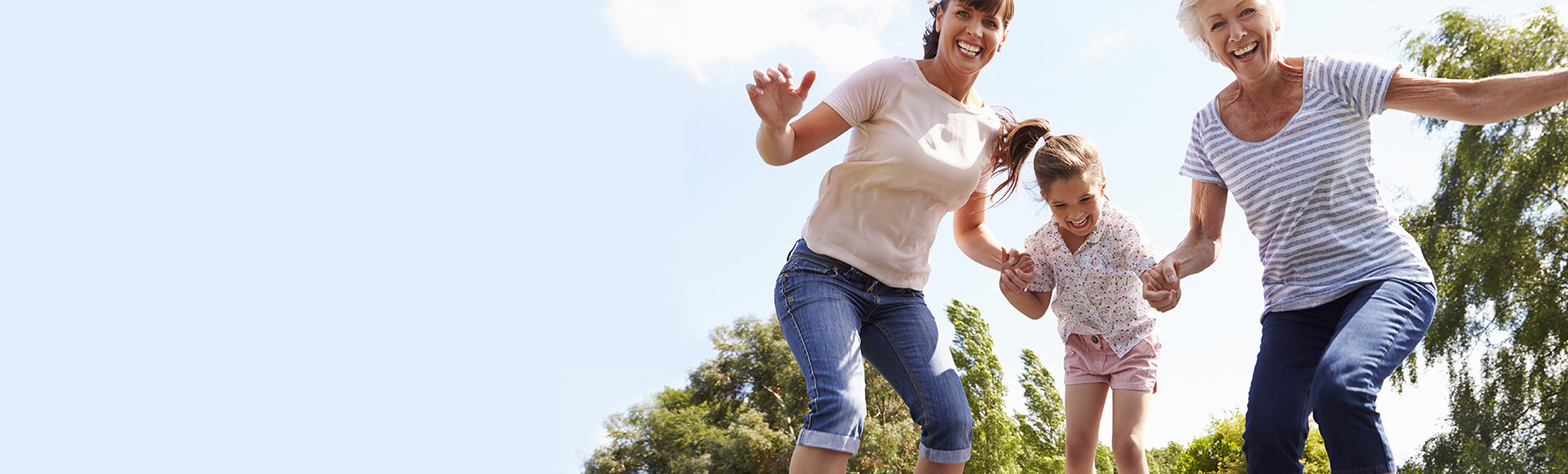 Grandmother, daughter, and granddaughter jumping on a trampoline.