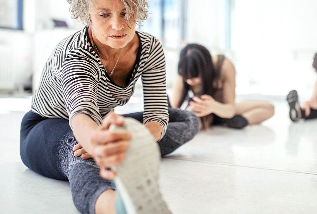 Focused woman stretches leg on floor.
