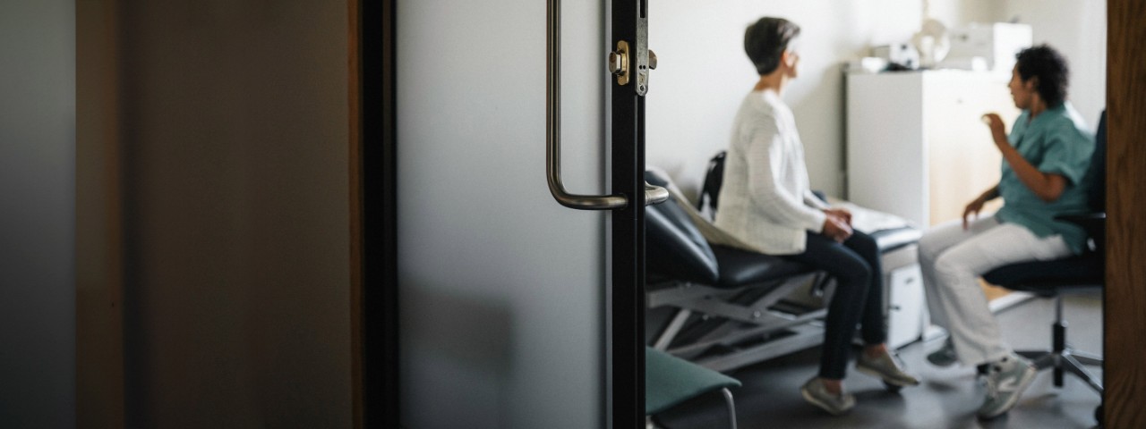 Healthcare provider discusses treatment options with woman on examination table. 