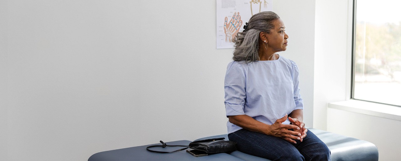 Female patient sitting on an exam table looking out a window.